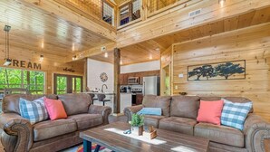 A spacious living area with two leather sofas, a wooden coffee table, and a colorful rug.