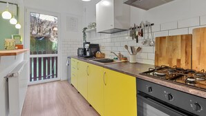Eine moderne Küche mit gelben Schränken, einem Gasherd und einem großen Fenster mit Blick auf einen Garten.