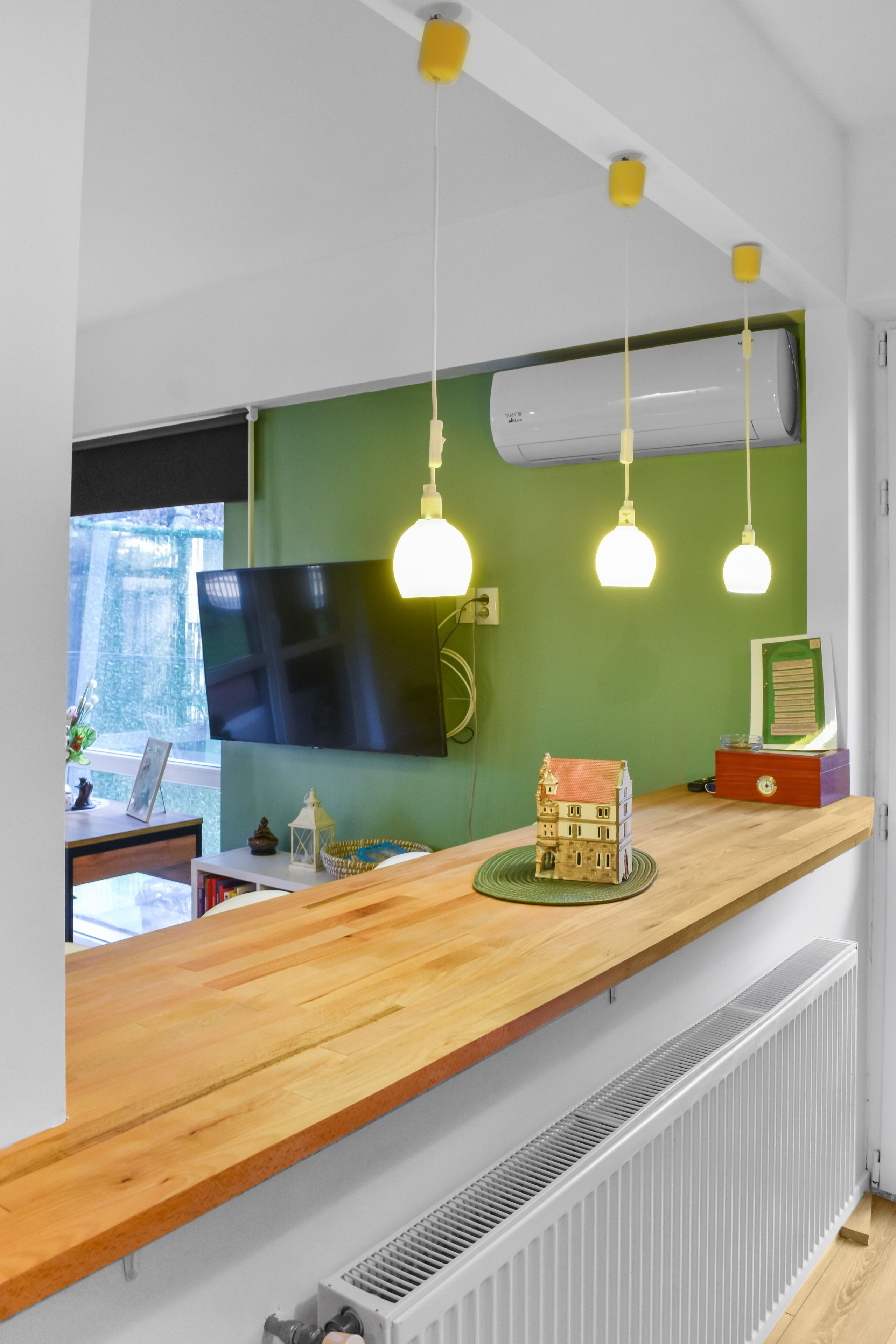 A modern reception area with a wooden counter, a flat-screen TV, and pendant lights.