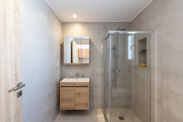 Une salle de bain moderne avec une douche à parois de verre, un meuble-lavabo en bois et un miroir au-dessus du lavabo.
