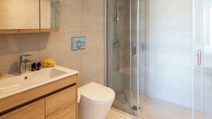 Un bagno moderno con un mobile bagno in legno, un box doccia in vetro e un water bianco.