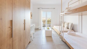 Une pièce moderne et bien éclairée, avec un lit superposé, un bureau blanc, une chaise et une vue sur l’extérieur grâce à une grande fenêtre.