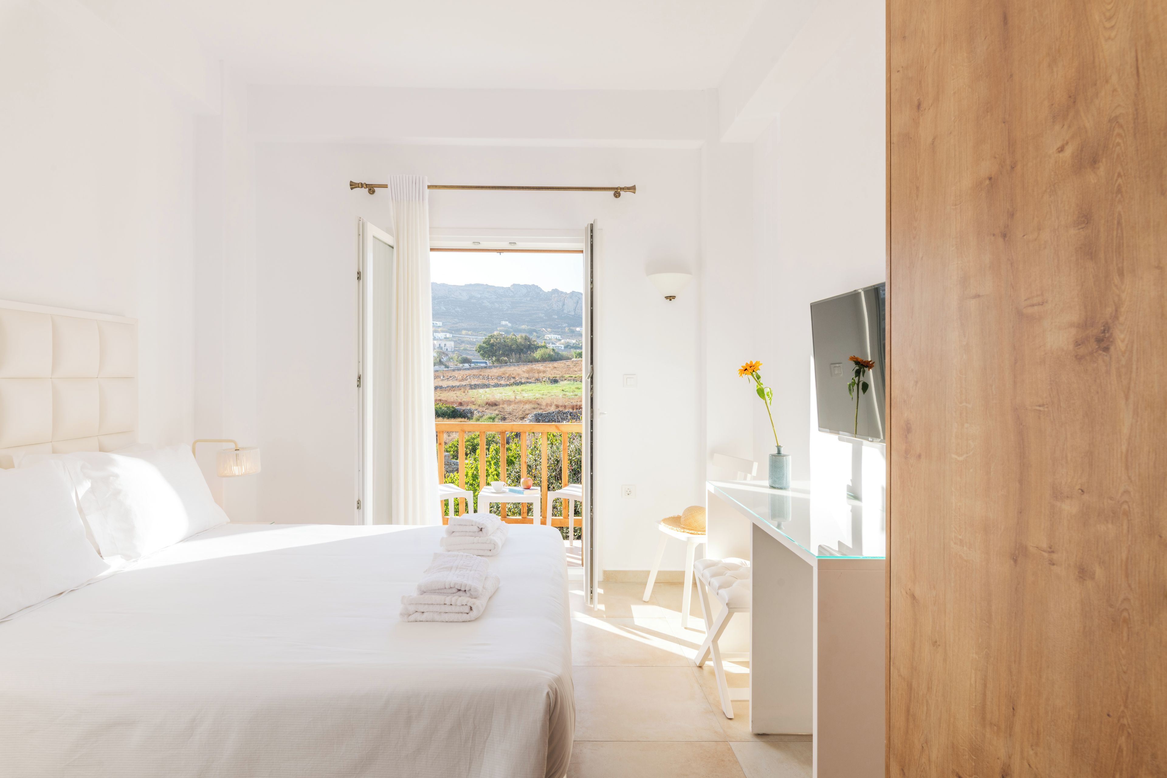 Un dormitorio con cama, escritorio y vistas al exterior.