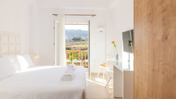 Une chambre à coucher avec un lit, un bureau et une vue sur l’extérieur.
