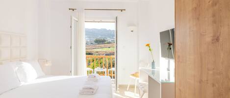 Un dormitorio con cama, escritorio y vistas al exterior.