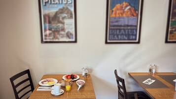 A dining area with two tables, each with a framed picture on the wall, a breakfast setting, and a view of the interior.