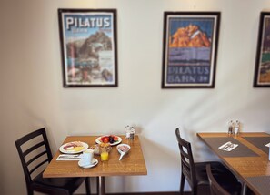 Un comedor con dos mesas, cada una con un cuadro enmarcado en la pared, una disposición para desayunar y vistas al interior.
