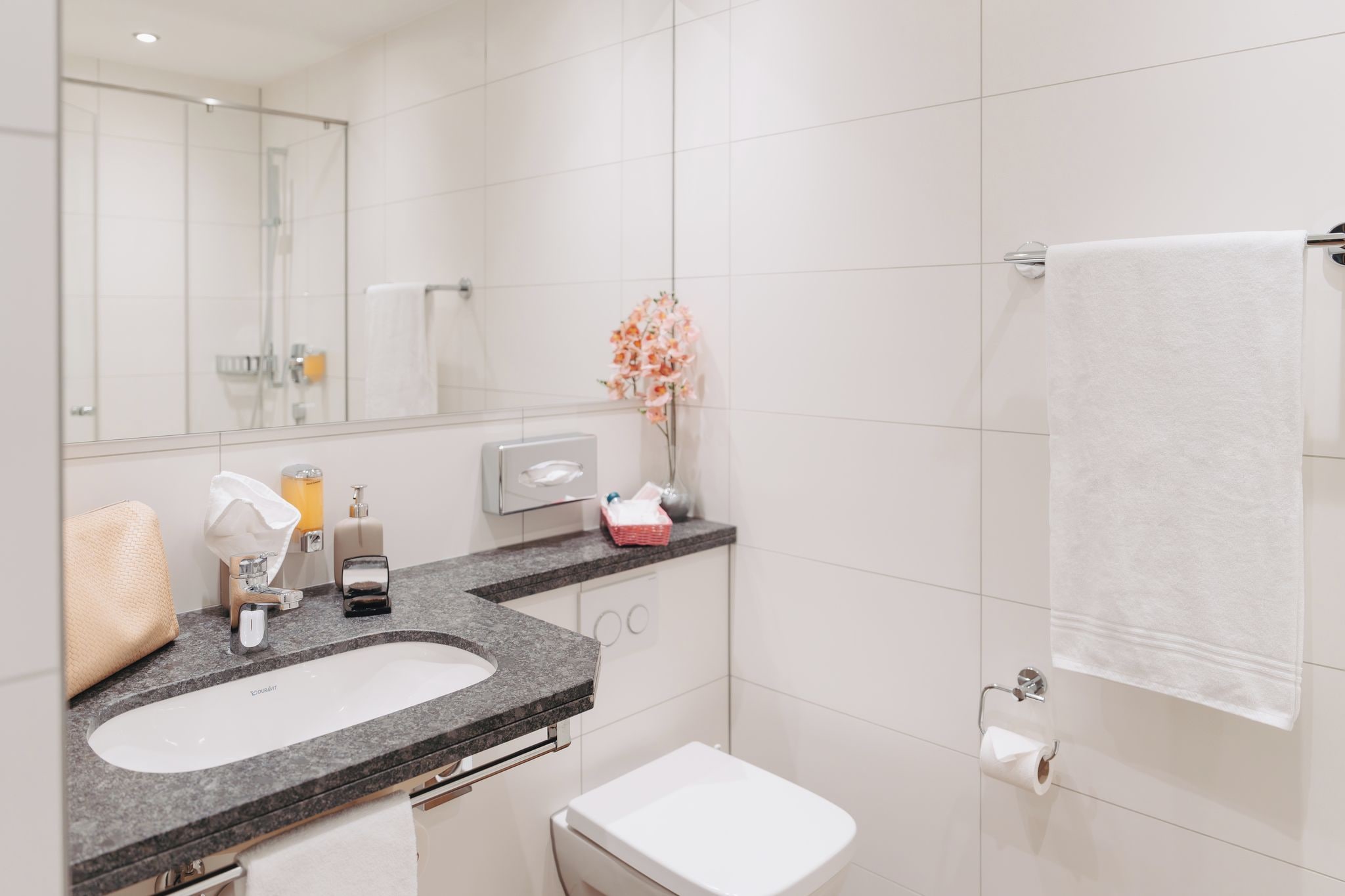 Un baño moderno con lavamanos, inodoro y perchero para toallas.
