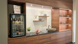 A modern kitchen with wooden cabinetry, a glass-fronted beverage cooler, a sink with a stone basin, and decorative shelves. - Gasthaus zur Waldegg, BW Signature Collection (Horw)