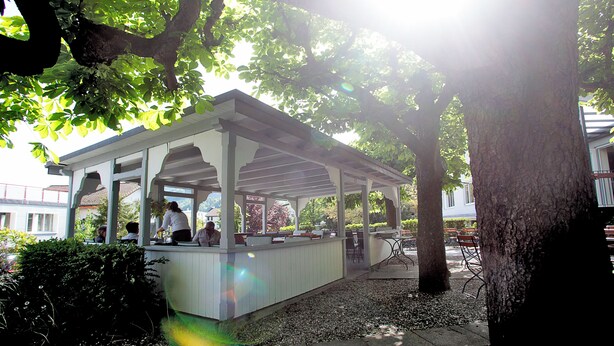 Un café al aire libre con zona de estar cubierta, mesas y sillas.