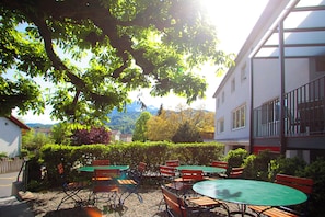 An outdoor seating area with tables and chairs, surrounded by greenery and a building. - Boutique Hotel Waldegg (Horw)