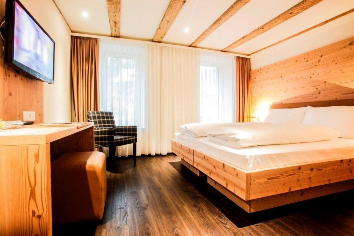 A wooden-paneled room with a bed, a desk, and a chair.