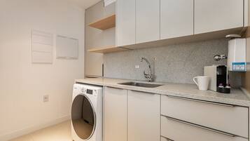 A modern kitchen with a built-in washer, a sink, and a coffee maker.