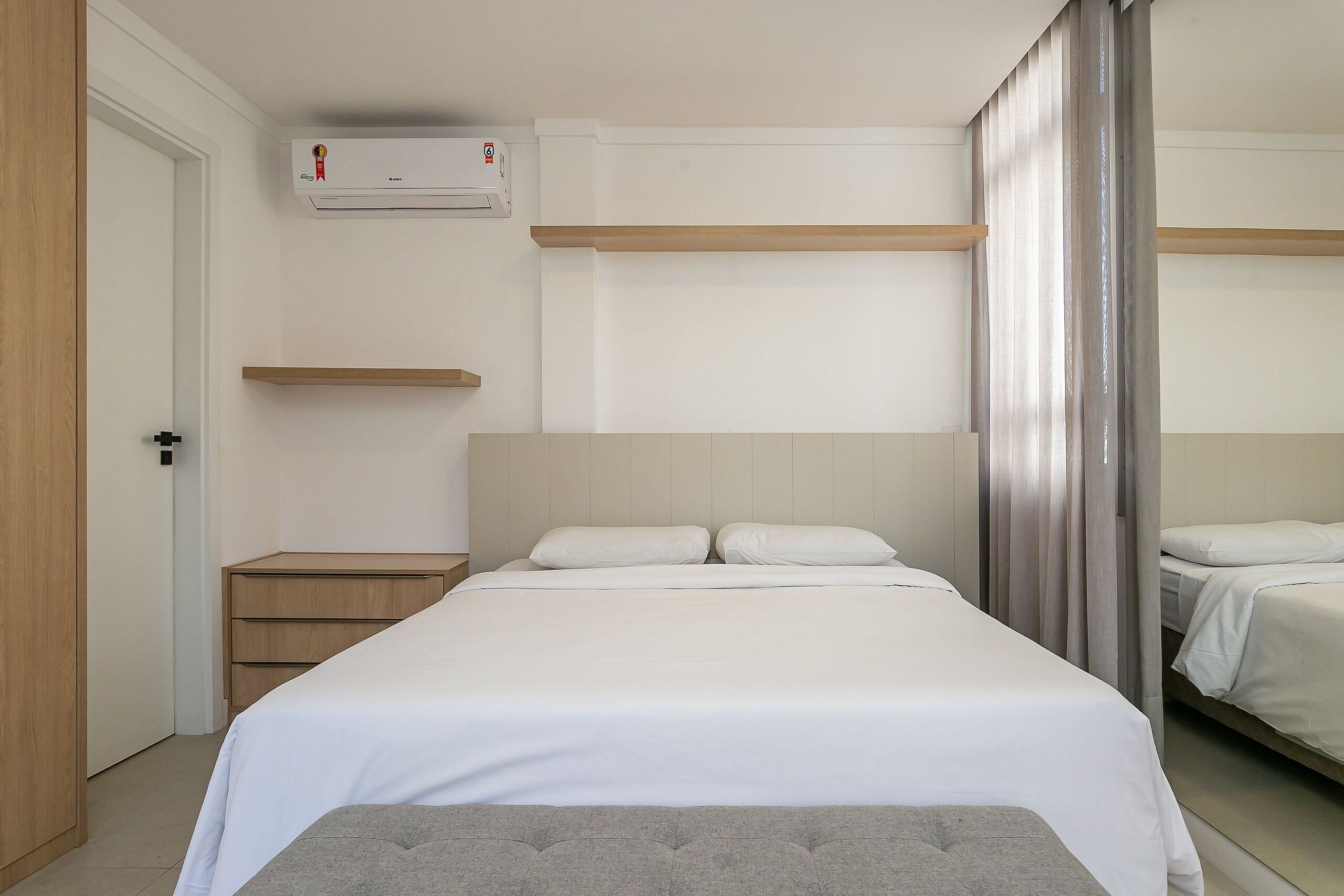 Un dormitorio con cama, mesita de noche, armario y ventana con cortinas.