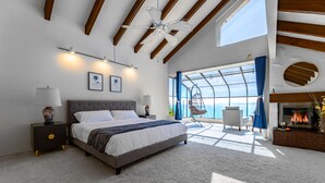Ein modernes Schlafzimmer mit einem großen Bett, einem Kamin und Meerblick.
