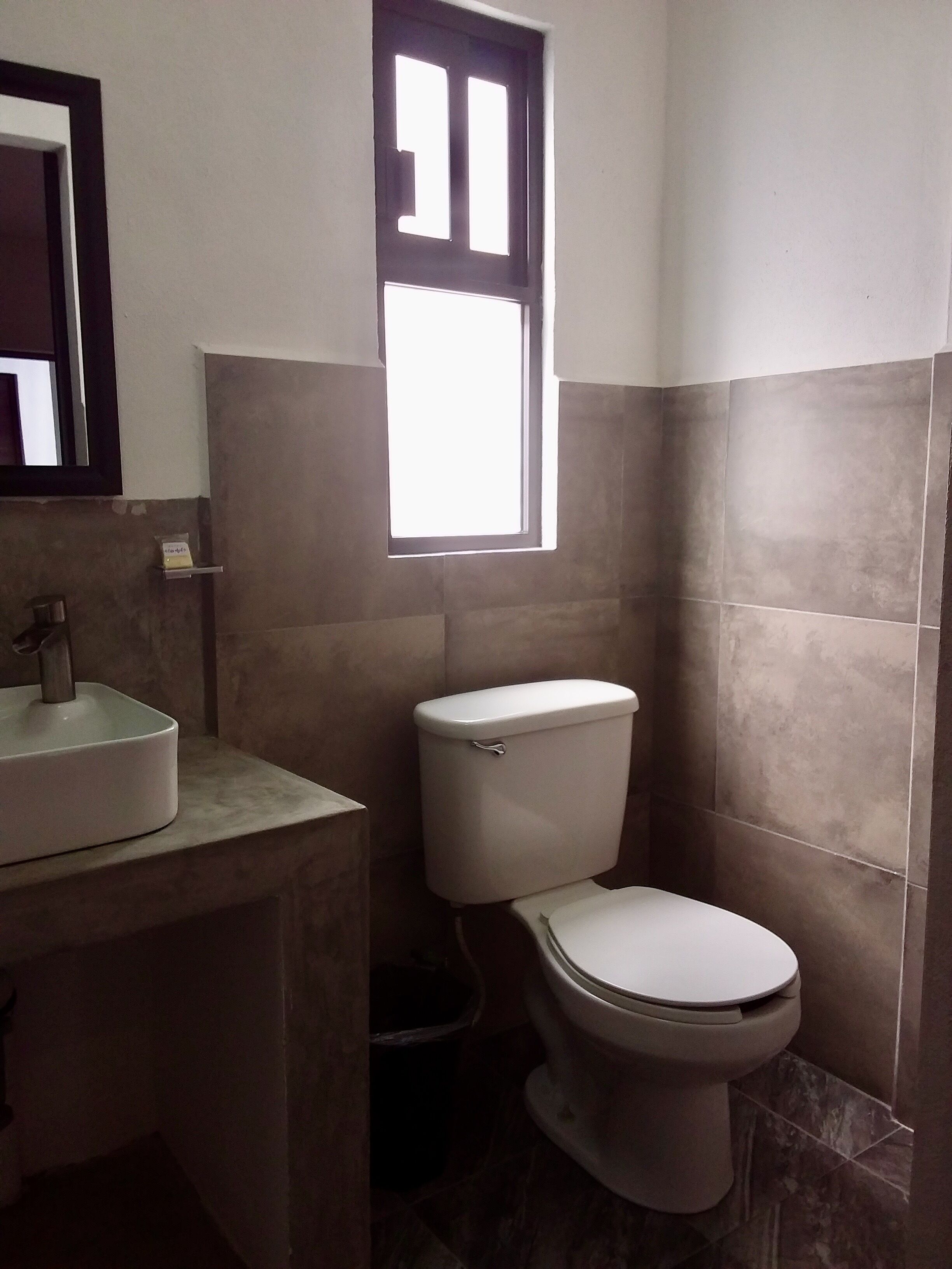 Un baño con inodoro, lavamanos y ventana.