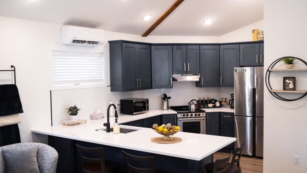 A modern kitchen with dark cabinets, stainless steel appliances, and a central island with bar stools.