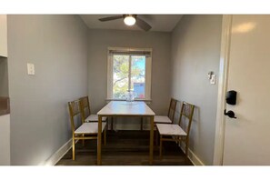 Enjoy meals in this cozy dining area with a table and four chairs, a ceiling fan, and a window offering a view of the outside.