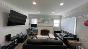 A modern living room with a flat-screen TV, a fireplace, a sofa, and a coffee table. - House-view & 5 min Walk to Beach (Hermosa Beach)