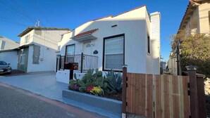 A single-story house with a white exterior, a small porch with a black railing, and a wooden fence in front. - House-view & 5 min Walk to Beach (Hermosa Beach)