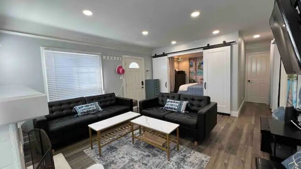 A modern living room with two black sofas, a coffee table, and a TV. - House-view & 5 min Walk to Beach (Hermosa Beach)