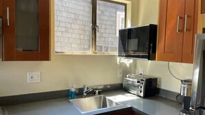 A kitchen with wooden cabinets, a microwave, a toaster, and a sink. - Large 1BR1BA with ocean view+walking to downtown (Sausalito)