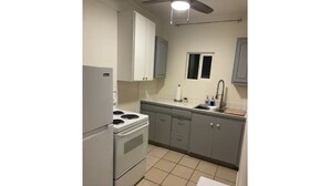 Una cocina con estufa, lavamanos y armarios.