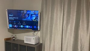 Un televisor de pantalla plana montado en la pared sobre un mueble bajo de color oscuro con varios cajones.