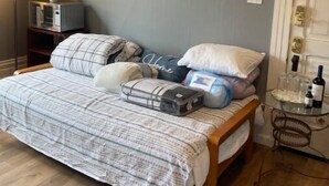 Une chambre à coucher avec un lit, des oreillers, une table de chevet avec une bouteille et une lampe.