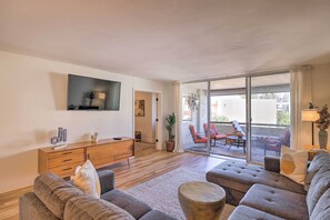 A modern living room with a sofa set, a wooden cabinet, a flat-screen TV, and a sliding glass door leading to an outdoor seating area. - Lounge Poolside: Resort Condo 1 Mi to Old Town! (Scottsdale)