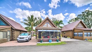 A log cabin-style building with a car parked in front, surrounded by palm trees and a clear sky. - Okeechobee Cabin in Waterfront Community w/ Dock! (Okeechobee)