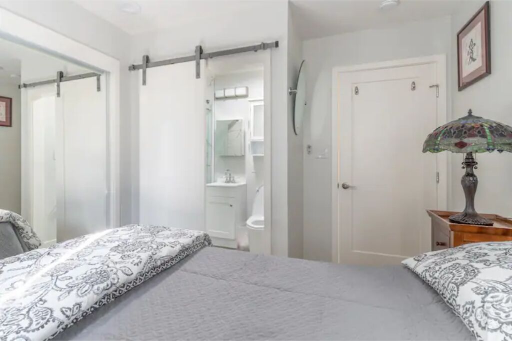 Une chambre avec deux lits, une armoire, un miroir et une table de chevet avec une lampe.