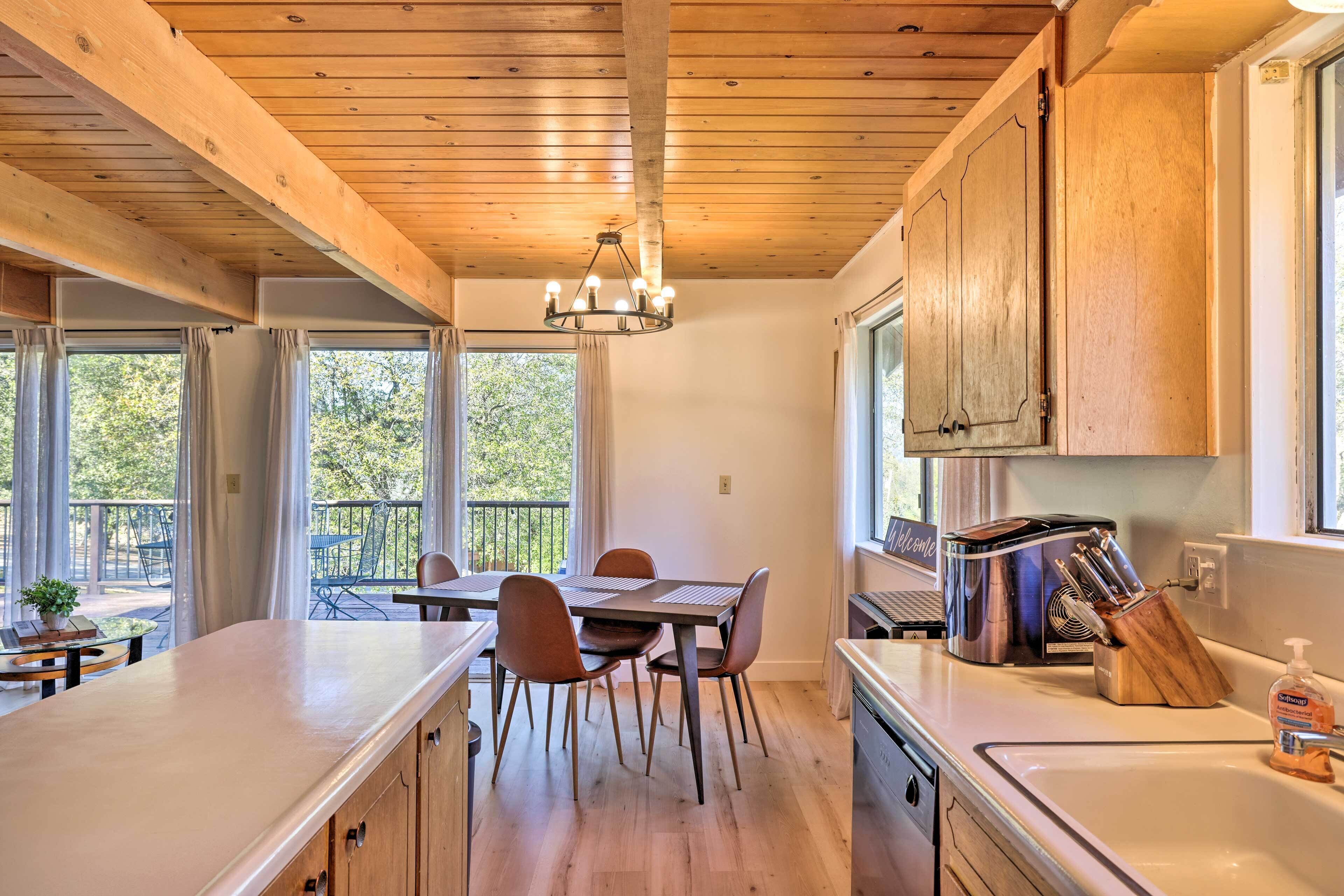 A modern kitchen with wooden beams, a dining area with a table and chairs, and a view of the outdoors.