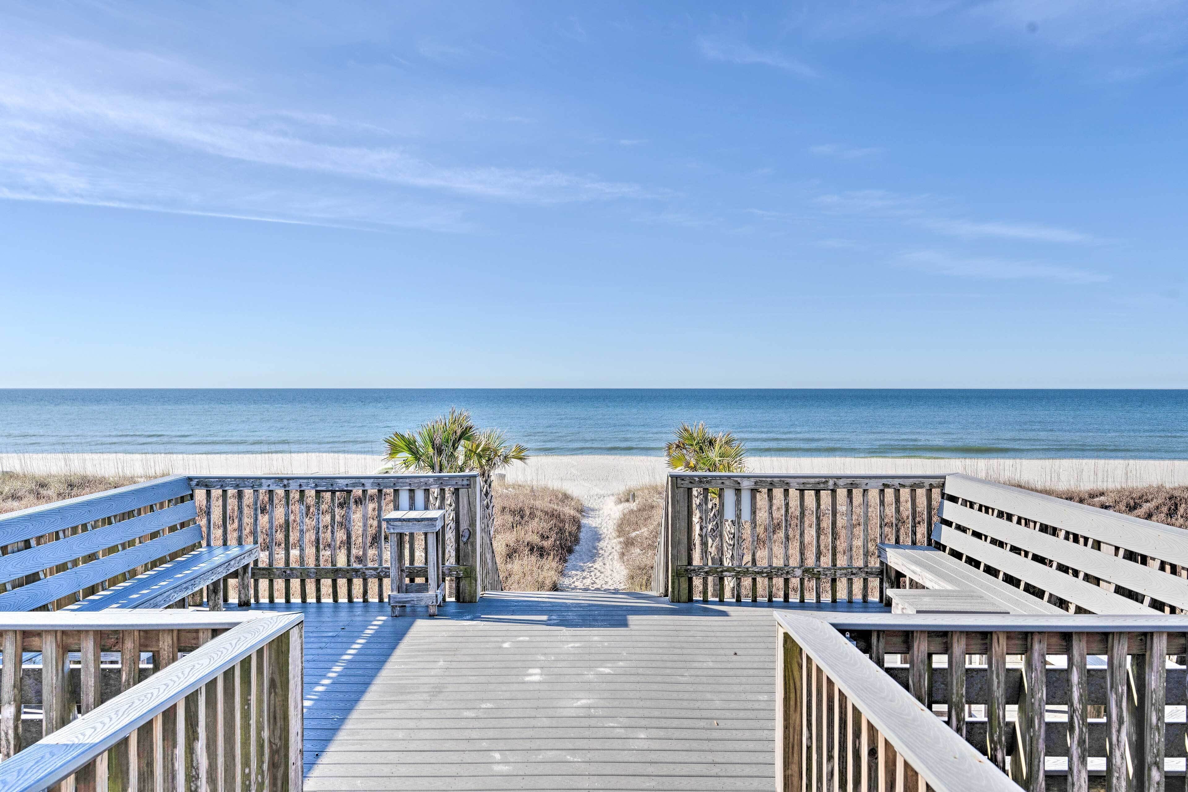 Una passerella di legno conduce a una spiaggia con vista libera sull'oceano.