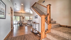 A spacious living area with a wooden staircase, a dining table, and a view of the outdoors. - McCall Home + Hot Tub ~ 2 Mi to Payette Lake (McCall)