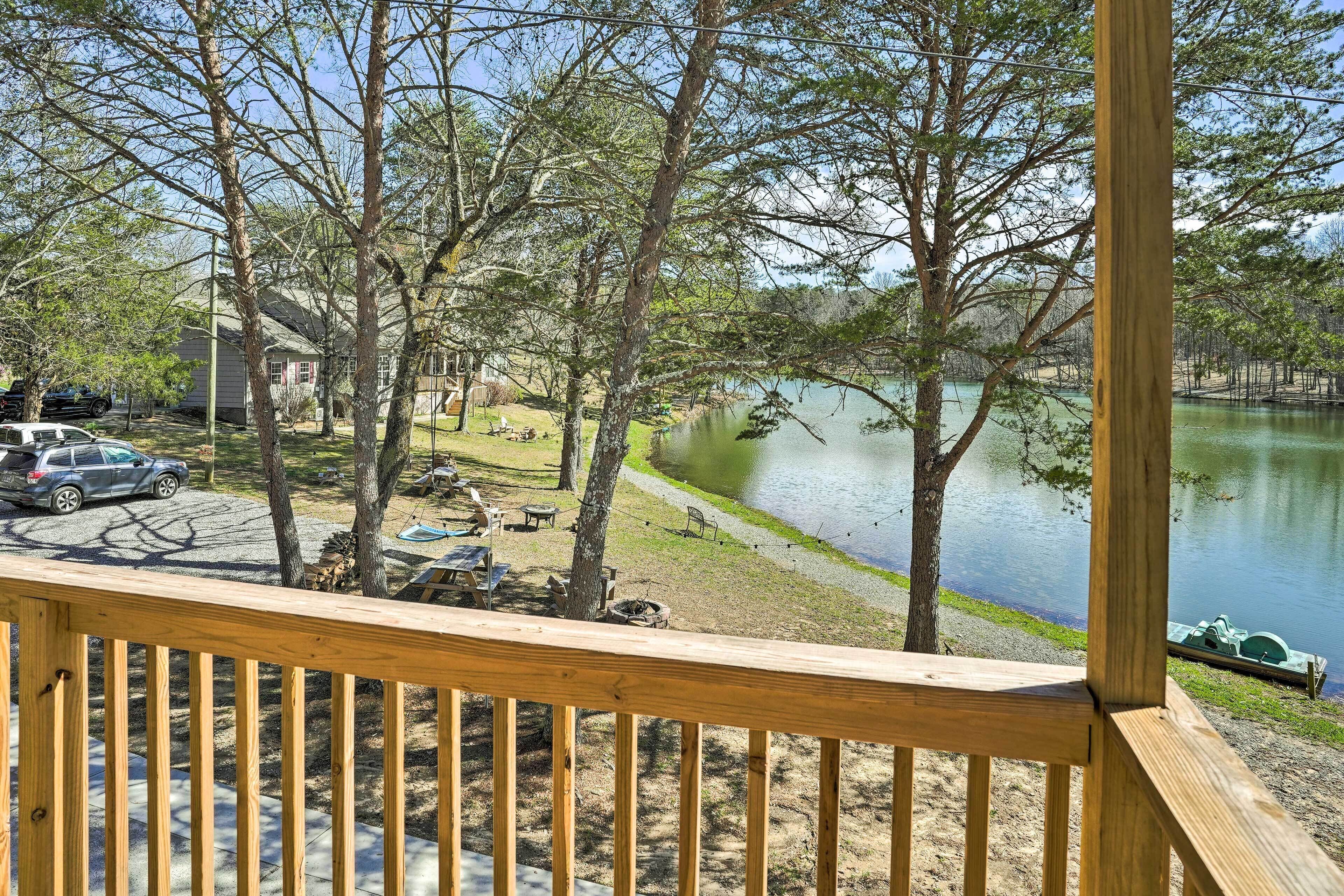 A wooden deck overlooking a lake with picnic tables and a boat dock.