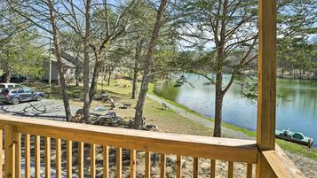 A wooden deck overlooking a lake with picnic tables and a boat dock.