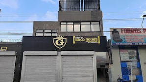 Un hôtel à la façade noire et ornée d’un emblème doré.