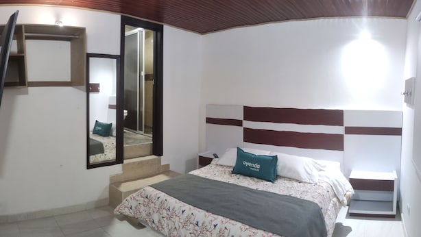 Une chambre à coucher avec un lit, un miroir, une table de chevet et un escalier.