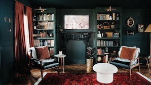 A cozy living room with a fireplace, bookshelves, two armchairs, and a coffee table.