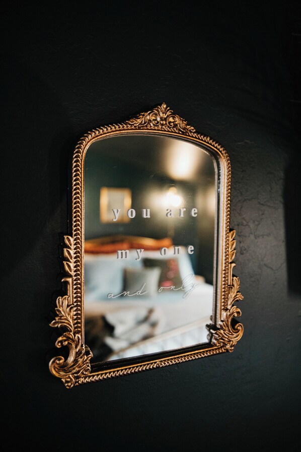 A mirror with an ornate gold frame reflecting a room interior.