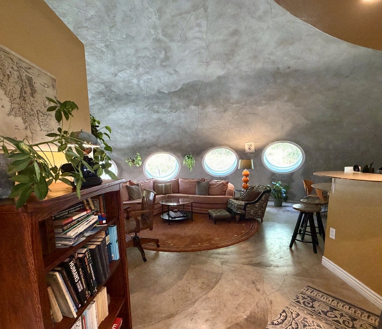 Ein gemütliches Wohnzimmer mit gewölbter Decke, einem Ecksofa, einem Couchtisch und einem Bücherregal.
