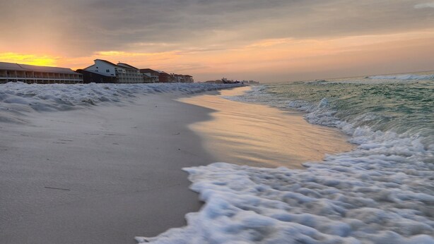 A beach with a row of buildings along the shore.