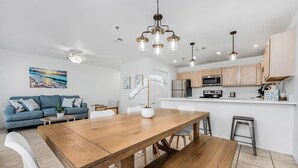 A modern kitchen with wooden cabinets, a central island, and a dining area with a wooden table and chairs.
