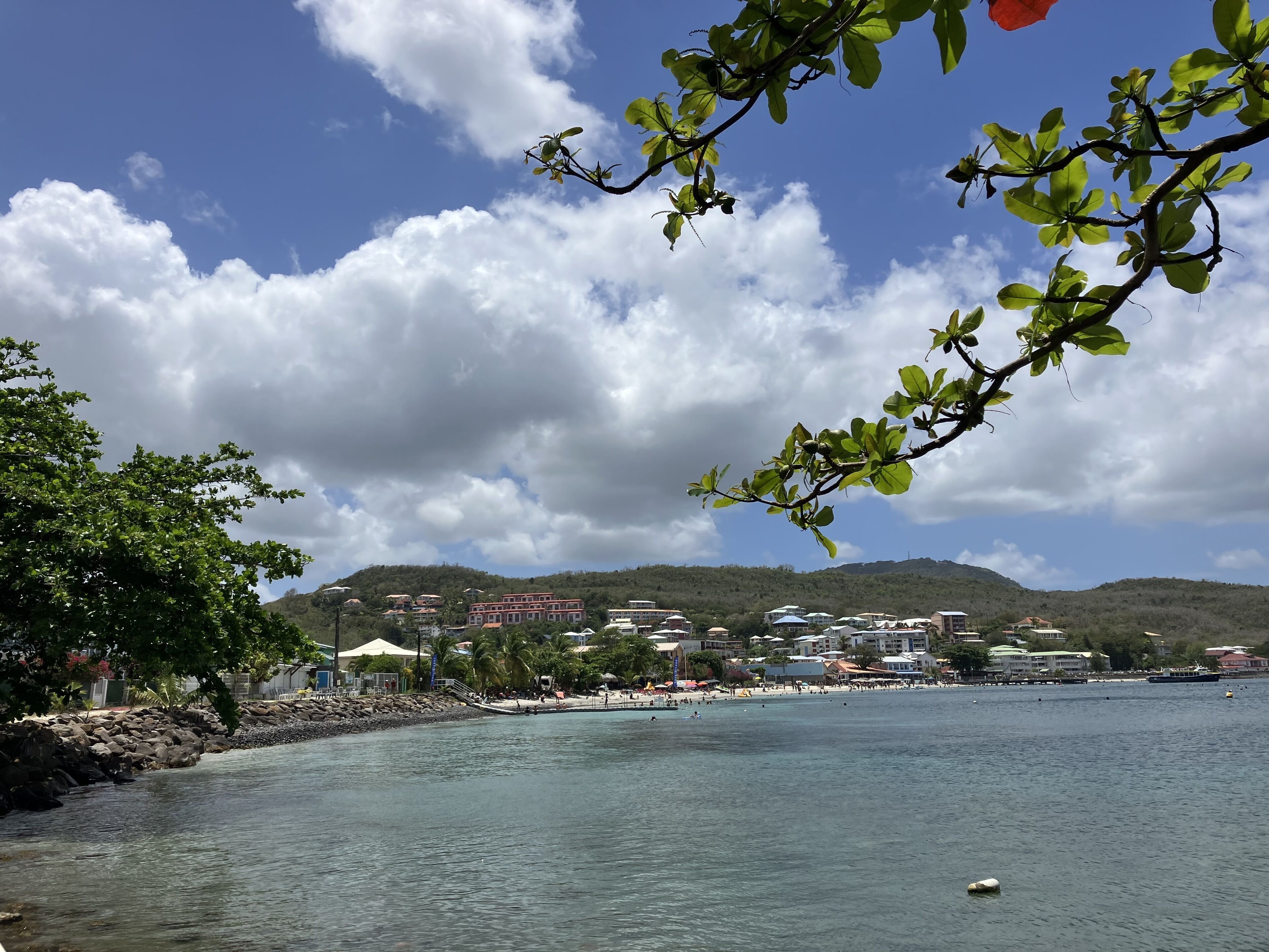 Une ville côtière avec une eau cristalline, une plage et des bâtiments en arrière-plan.