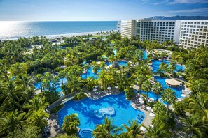 Un resort con varias piscinas rodeadas de palmeras y vistas al océano.