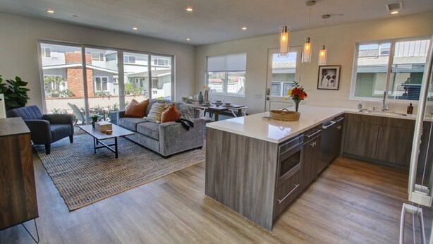 Una cocina moderna con una isla central, ventanas amplias y una zona de comedor con sofá y mesa de centro.