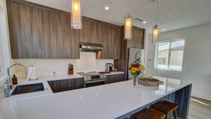 Una cocina moderna con una isla grande, electrodomésticos de acero inoxidable y armarios de madera.