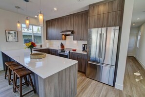 Una cocina moderna con una isla central, electrodomésticos de acero inoxidable y armarios de madera.