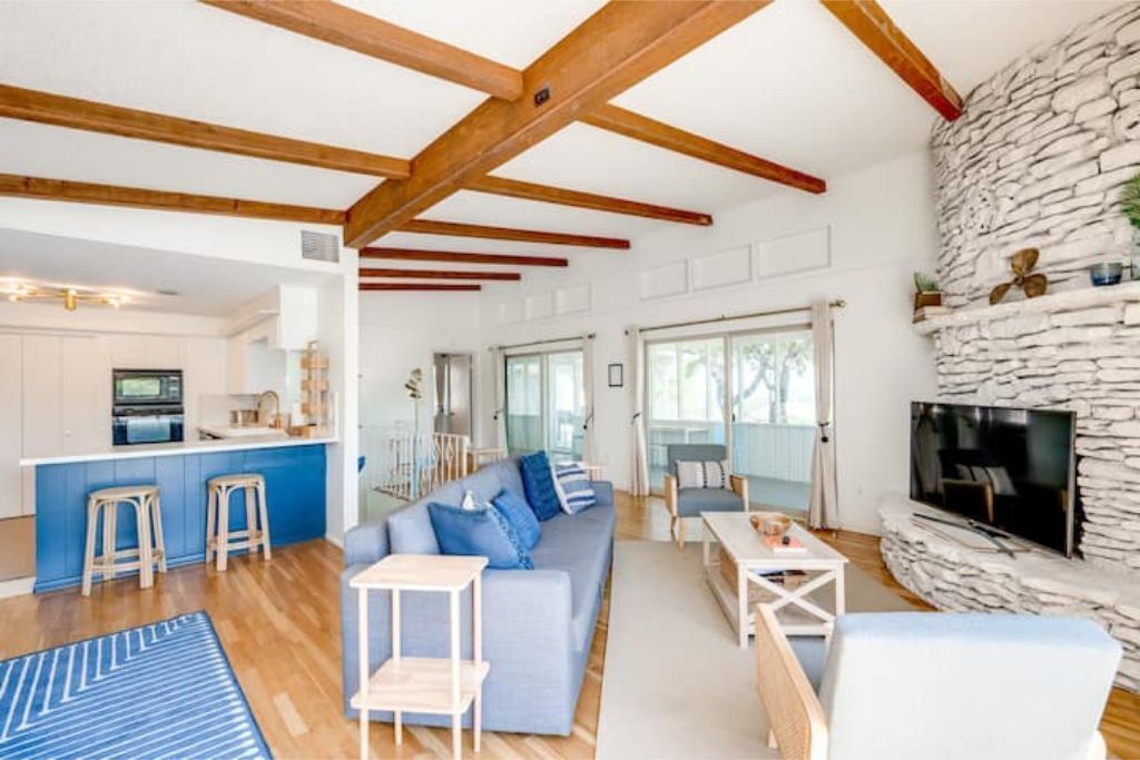 A modern living room with a blue sofa, a coffee table, and a stone fireplace.
